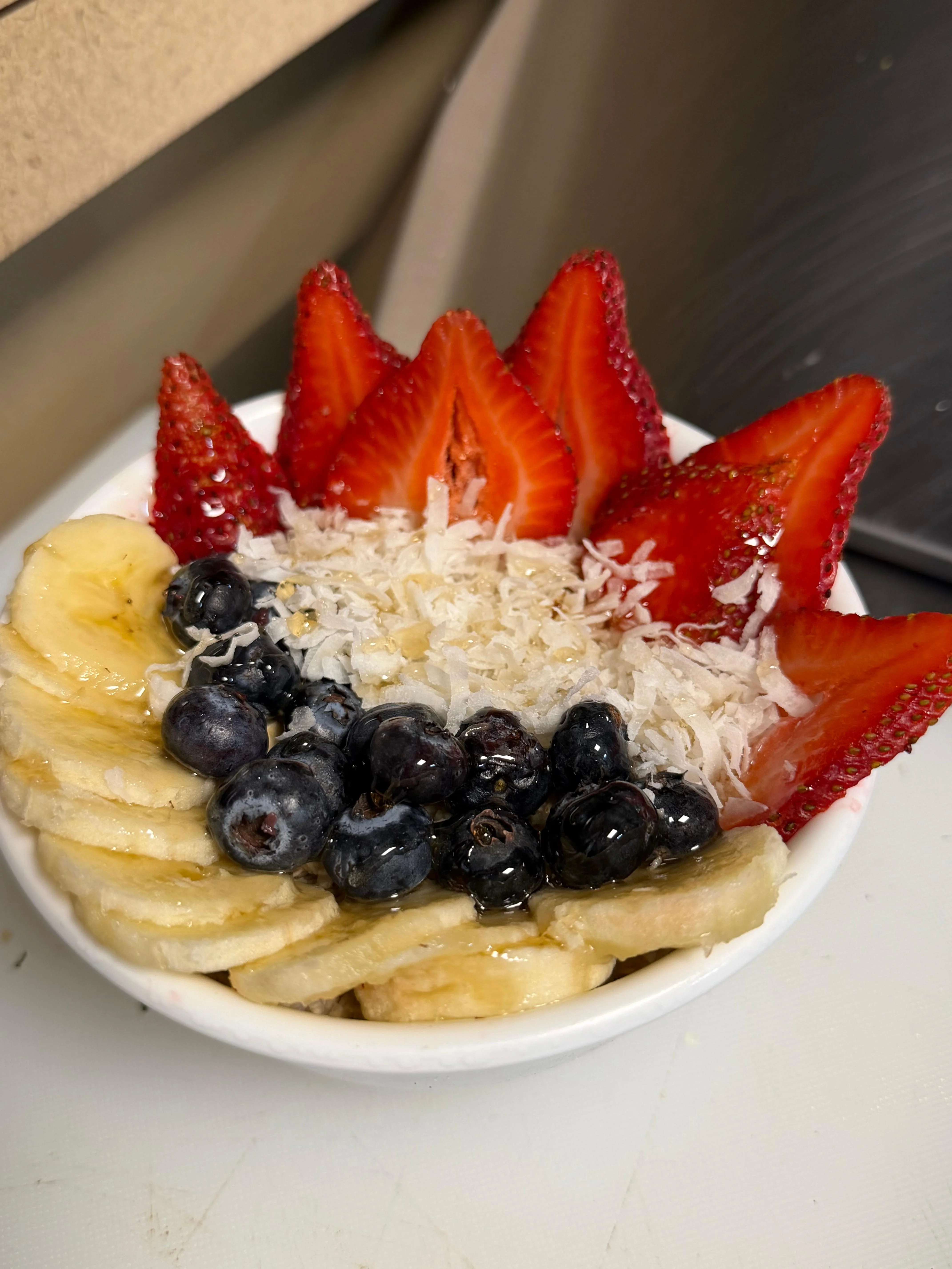 A vibrant fruit bowl featuring slices of banana, strawberries, blueberries, and shredded coconut, arranged in a decorative manner.