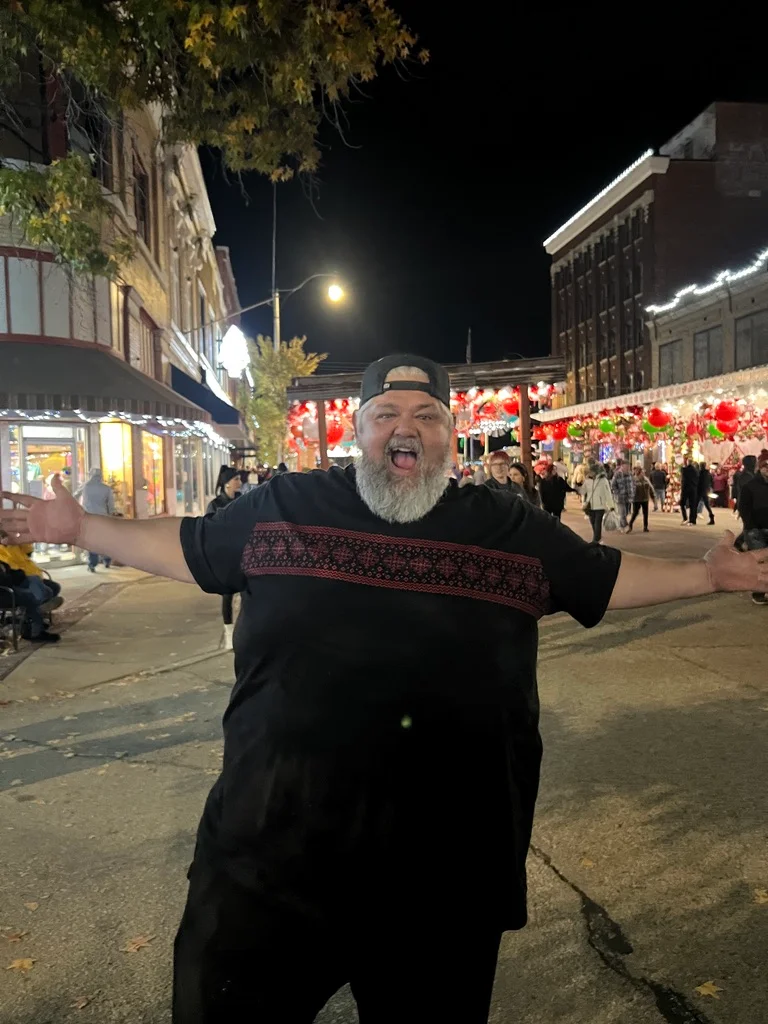 Person celebrating at a festive street event with colorful decorations