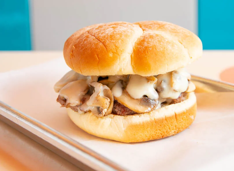 Delicious gourmet burger with fresh toppings on a wooden table.