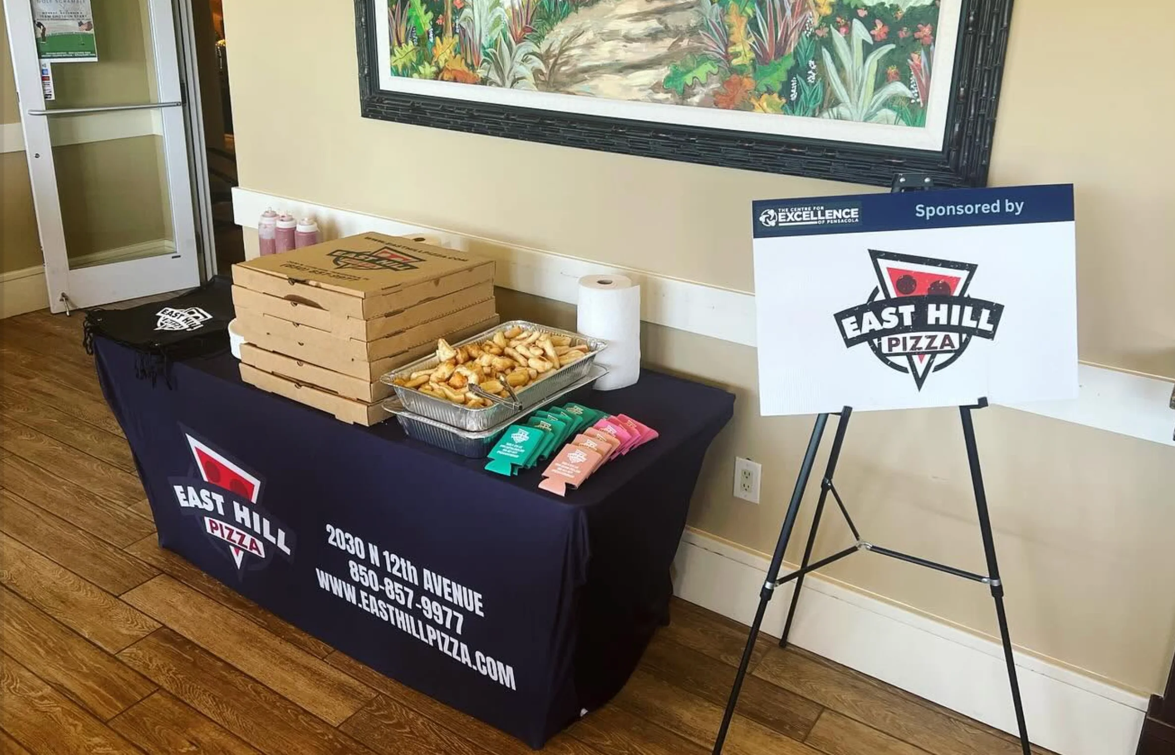Pizza catering table with boxed pizzas, breadsticks, and restaurant branding