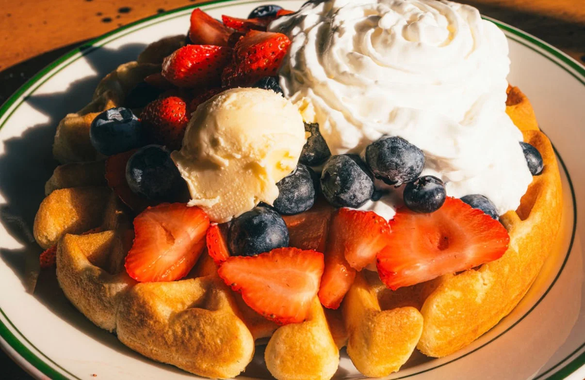 Belgian waffle topped with fresh berries and whipped cream