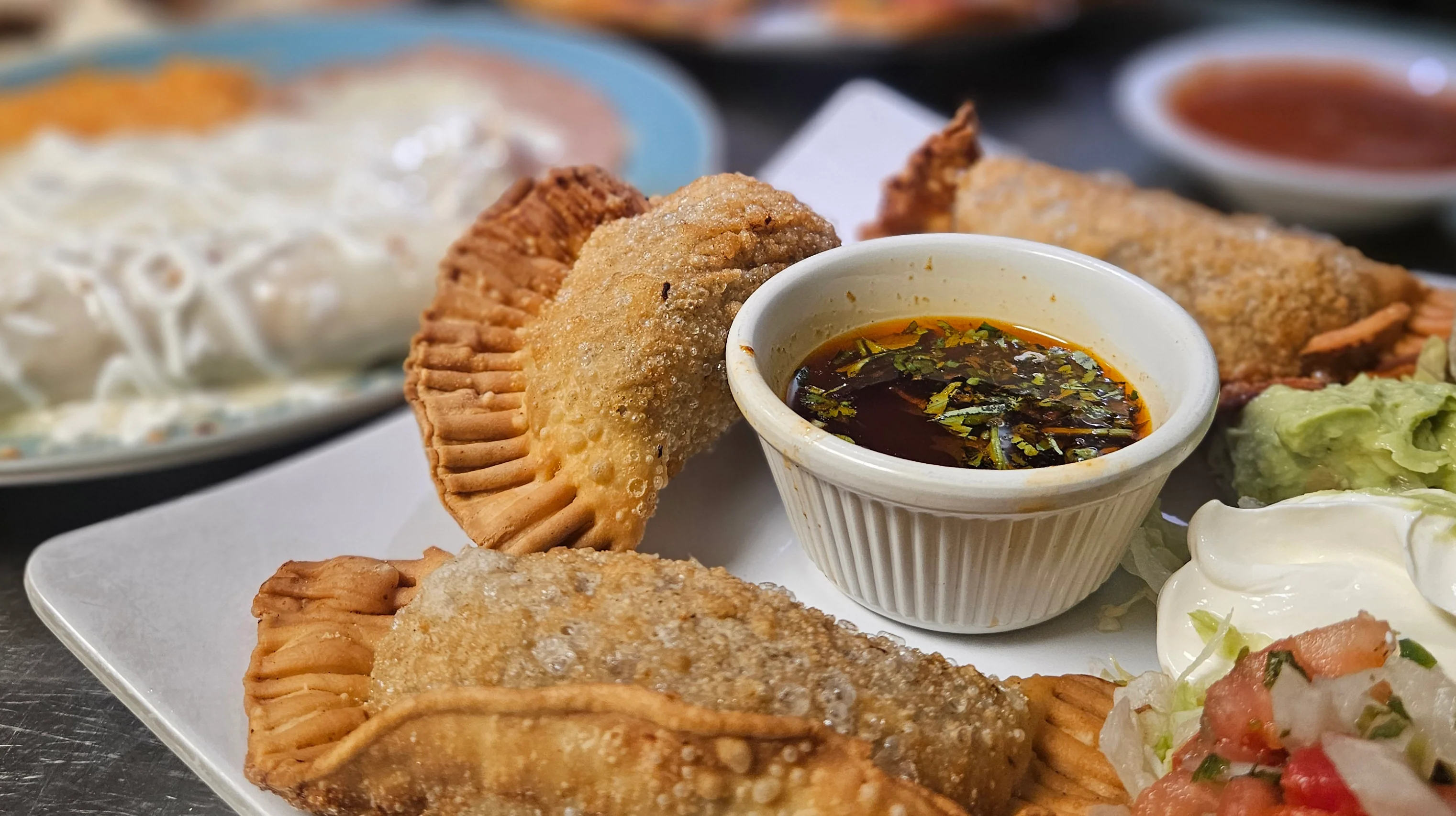 Crispy empanadas with dipping sauce and fresh toppings