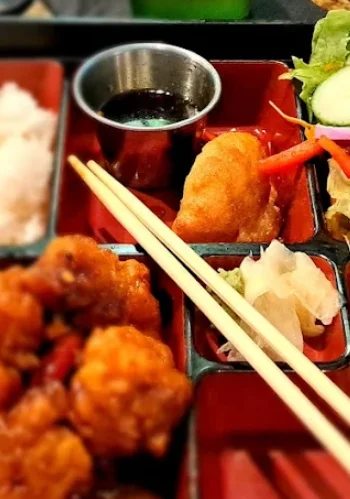 Japanese bento box with chicken, sushi, and salad