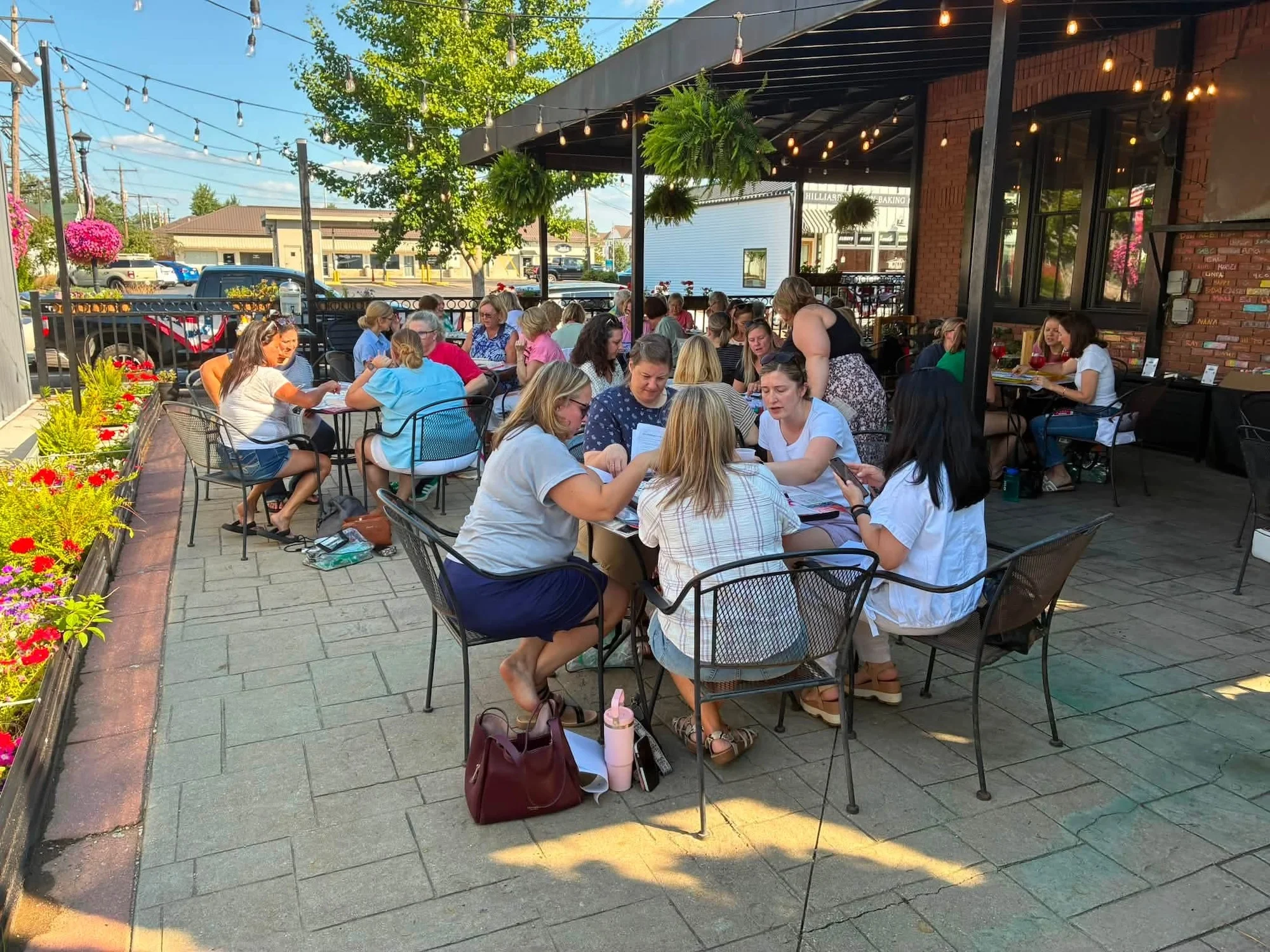 A lively outdoor dining space filled with groups of people gathered around tables, enjoying food and conversation.