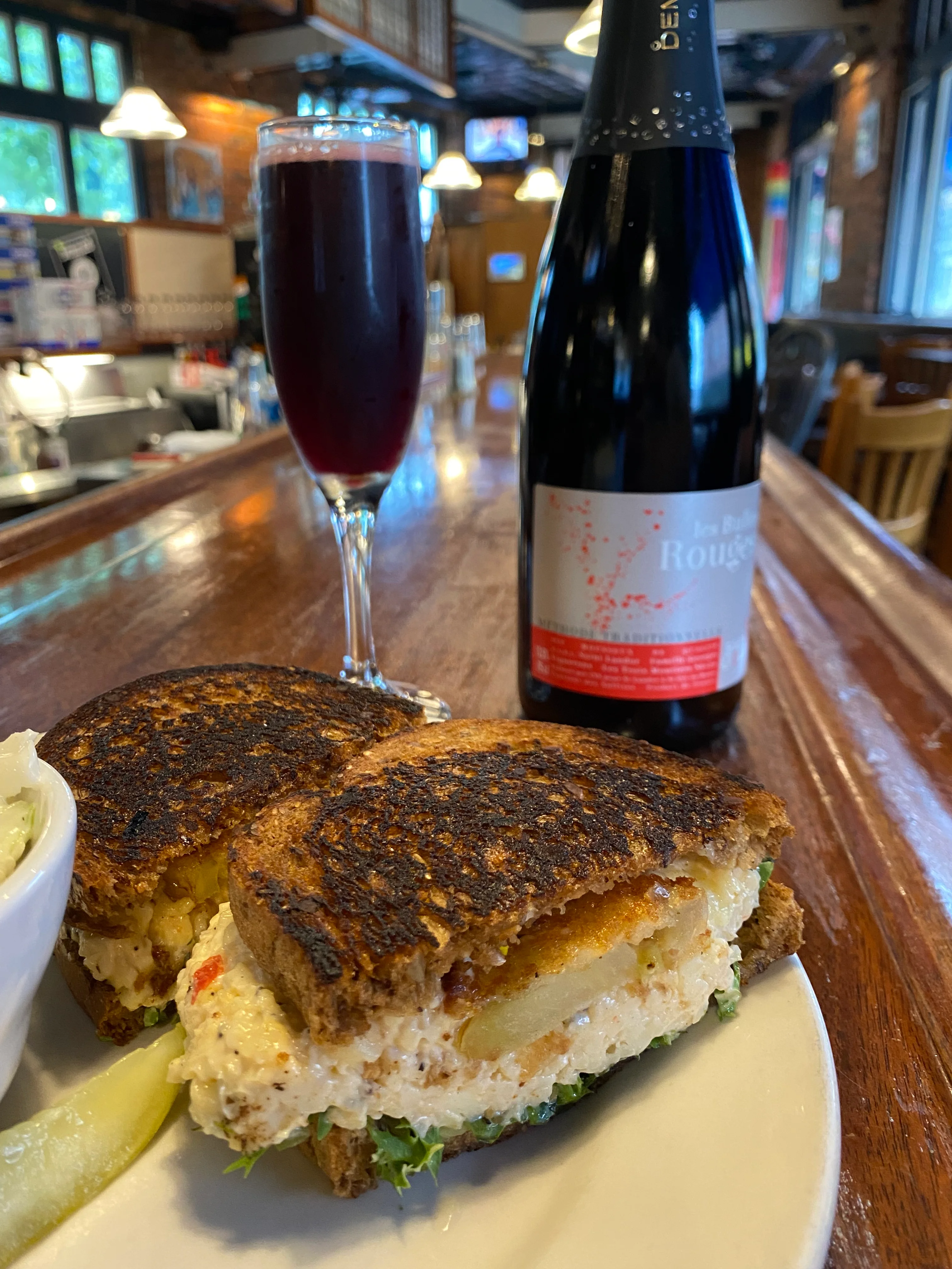 Grilled cheese sandwich with a side of pickles and a sparkling beverage