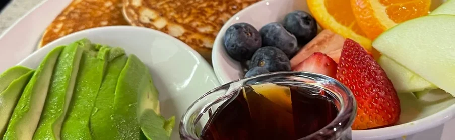 Fluffy pancakes with fresh fruit and avocado slices