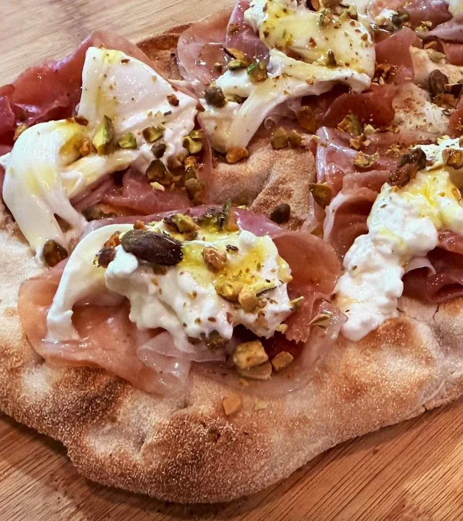 La Pistacchiosa Pinsa Romana served with Burrata, Prosciutto di Parma, Pistachios and hot honey at Daje Pinsa Roman Pizza, Orlando