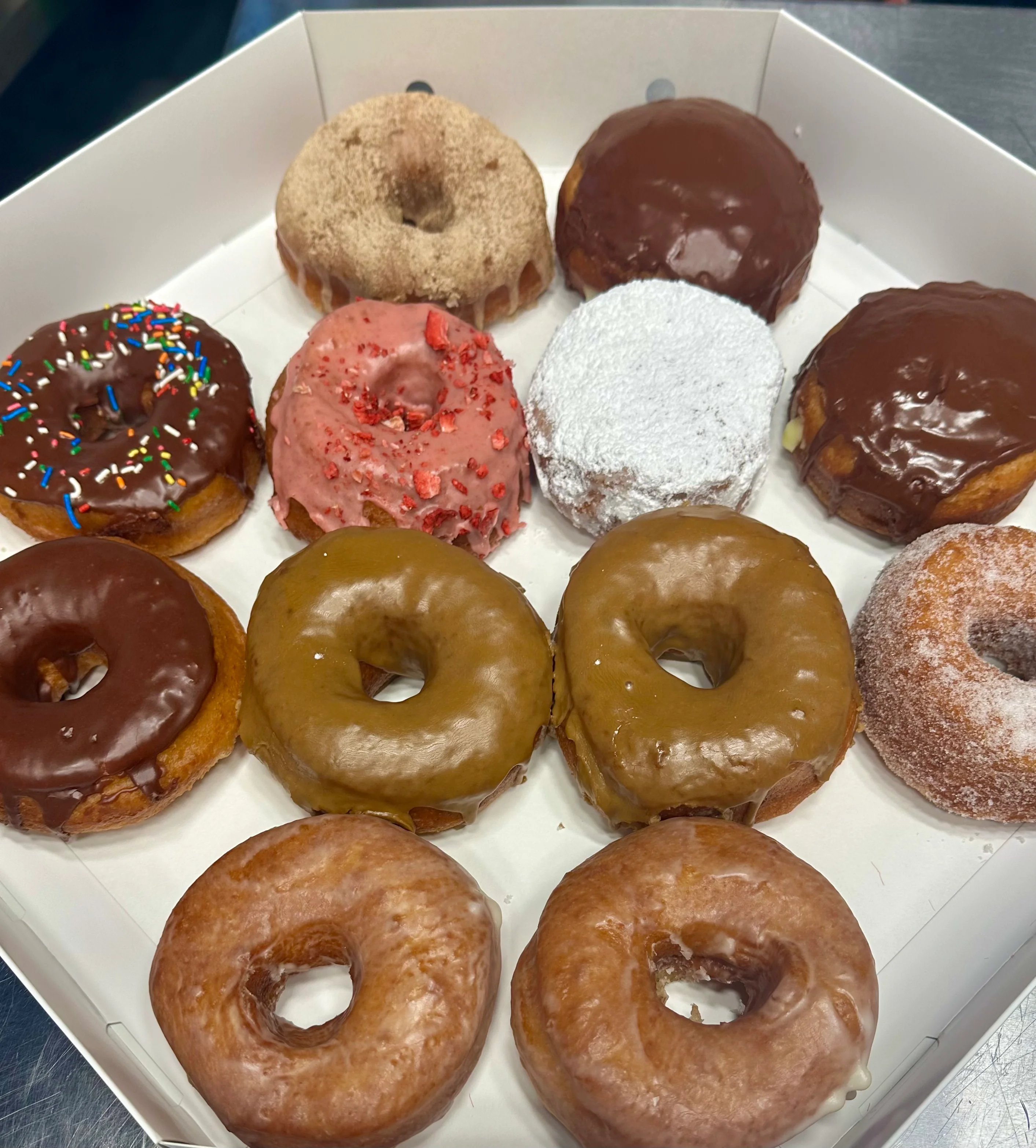 Assorted gourmet donuts in a white box
