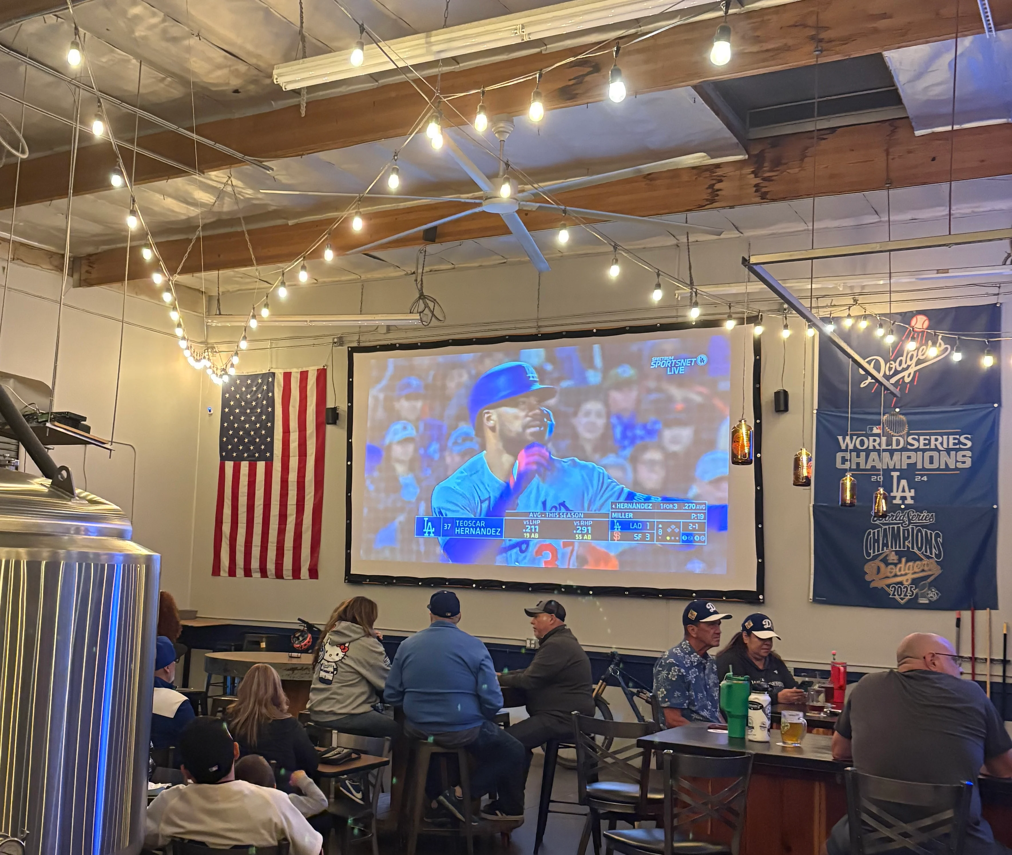 Cozy brewery interior with patrons watching a game on a large screen