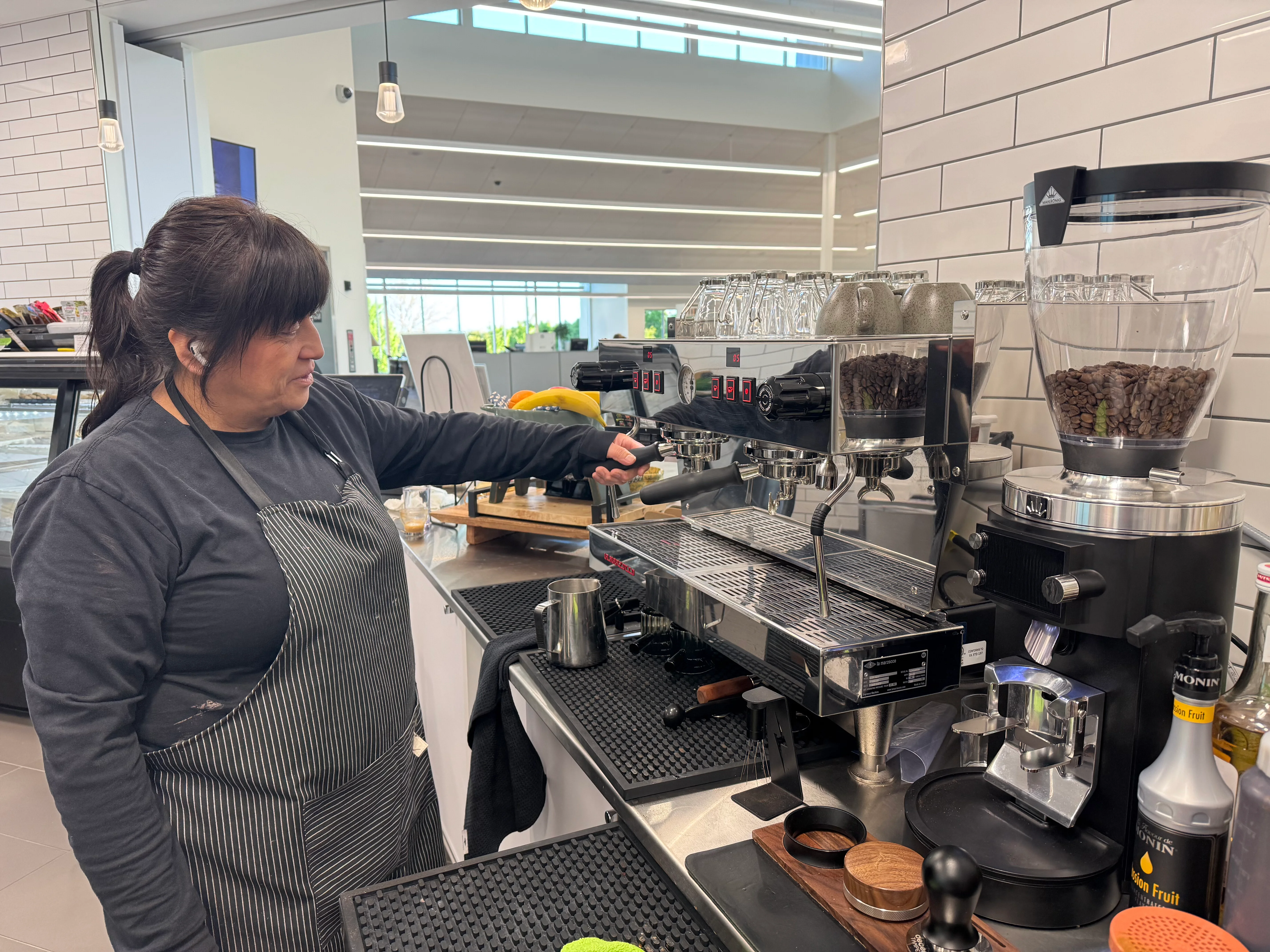 Barista preparing coffee at a modern café with La Marzocco espresso machine.
