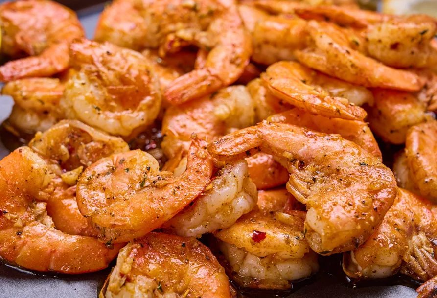 A bountiful seafood platter filled with a variety of shellfish, including lobster, shrimp, and crab, accompanied by potatoes, corn, and lemon wedges.