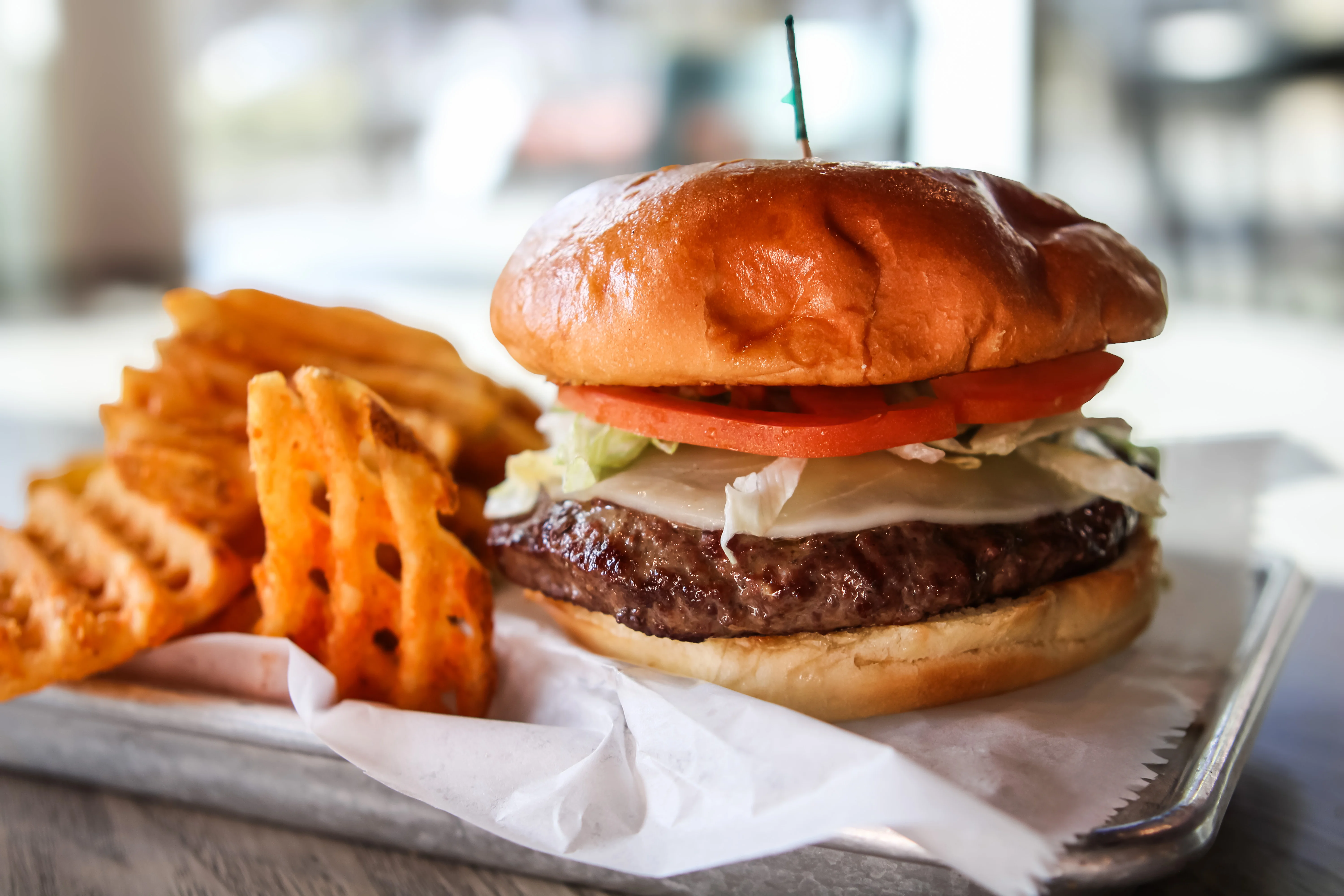 Close-up of stacked cheeseburgers with sesame buns and fresh toppings