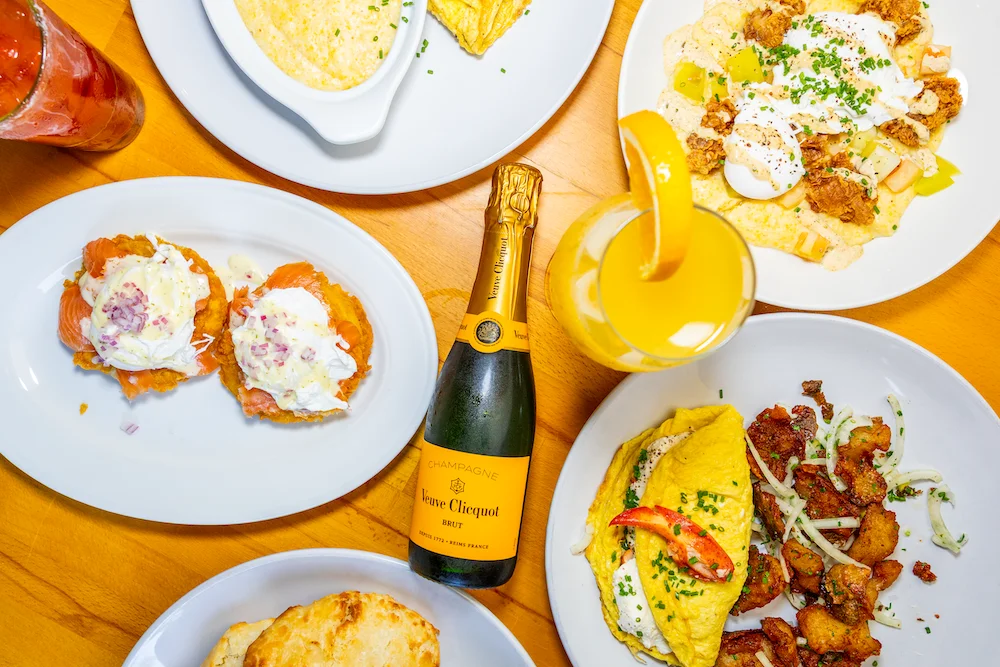 Brunch spread with champagne, omelette, and various dishes on a wooden table.
