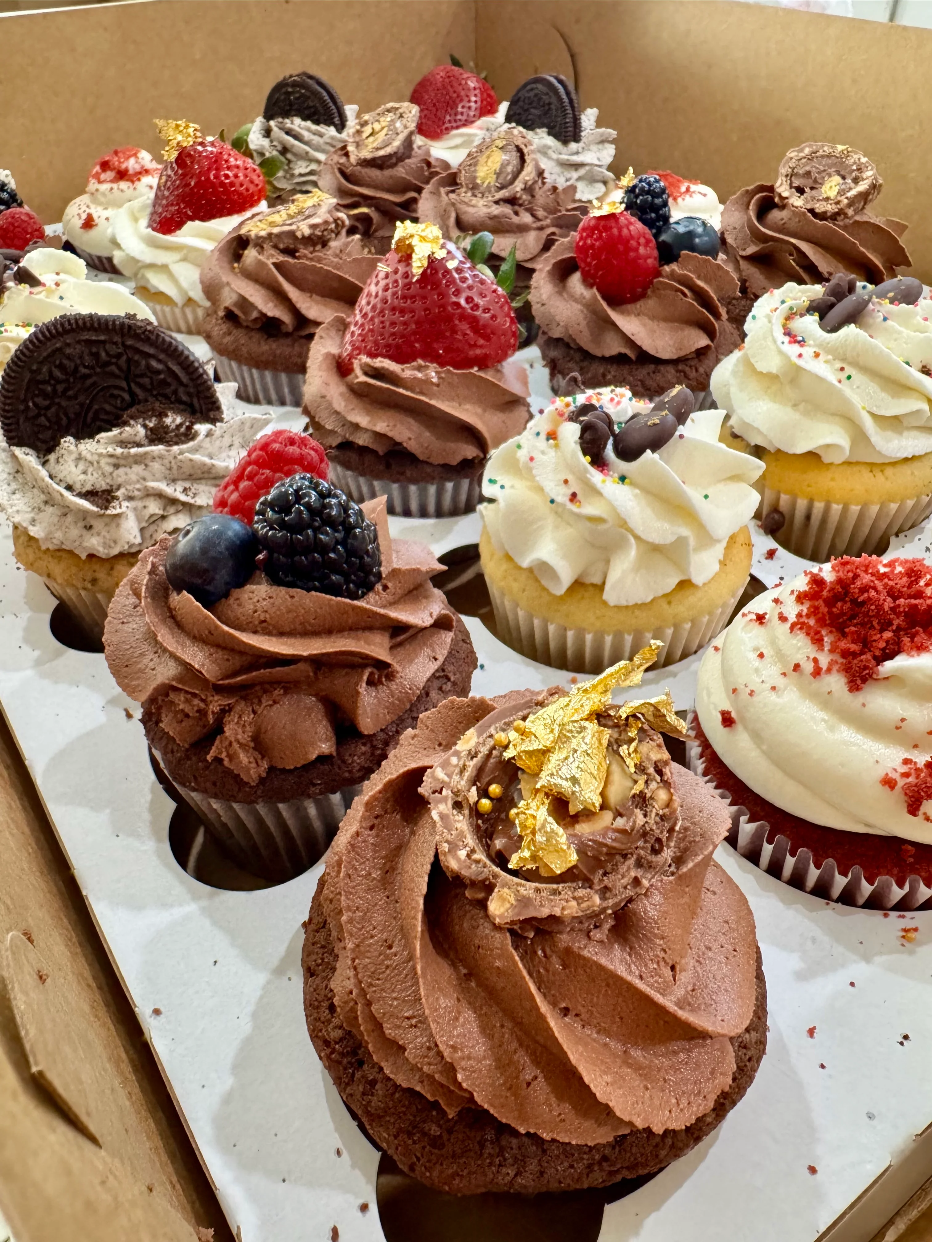Assorted gourmet cupcakes in a decorative box