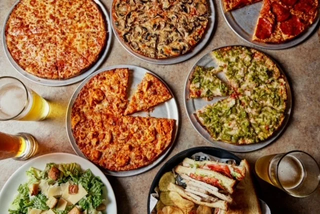 Variety of pizzas and a sandwich platter in a casual dining setting