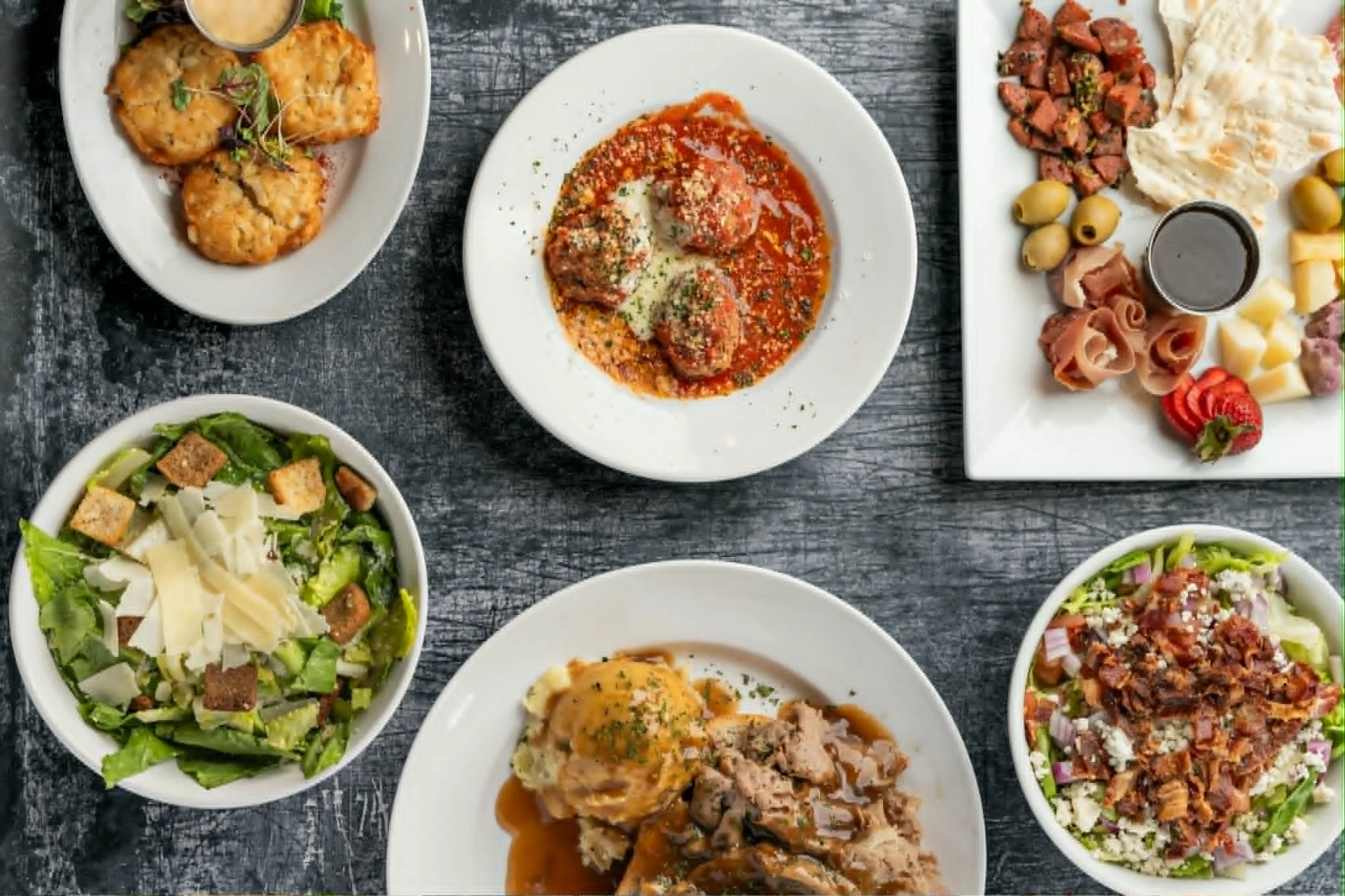 Italian meatballs in marinara sauce with sides of salads and appetizers