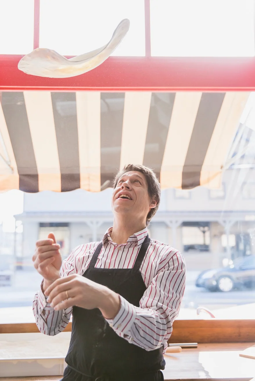 Chef tossing pizza dough in a cozy pizzeria