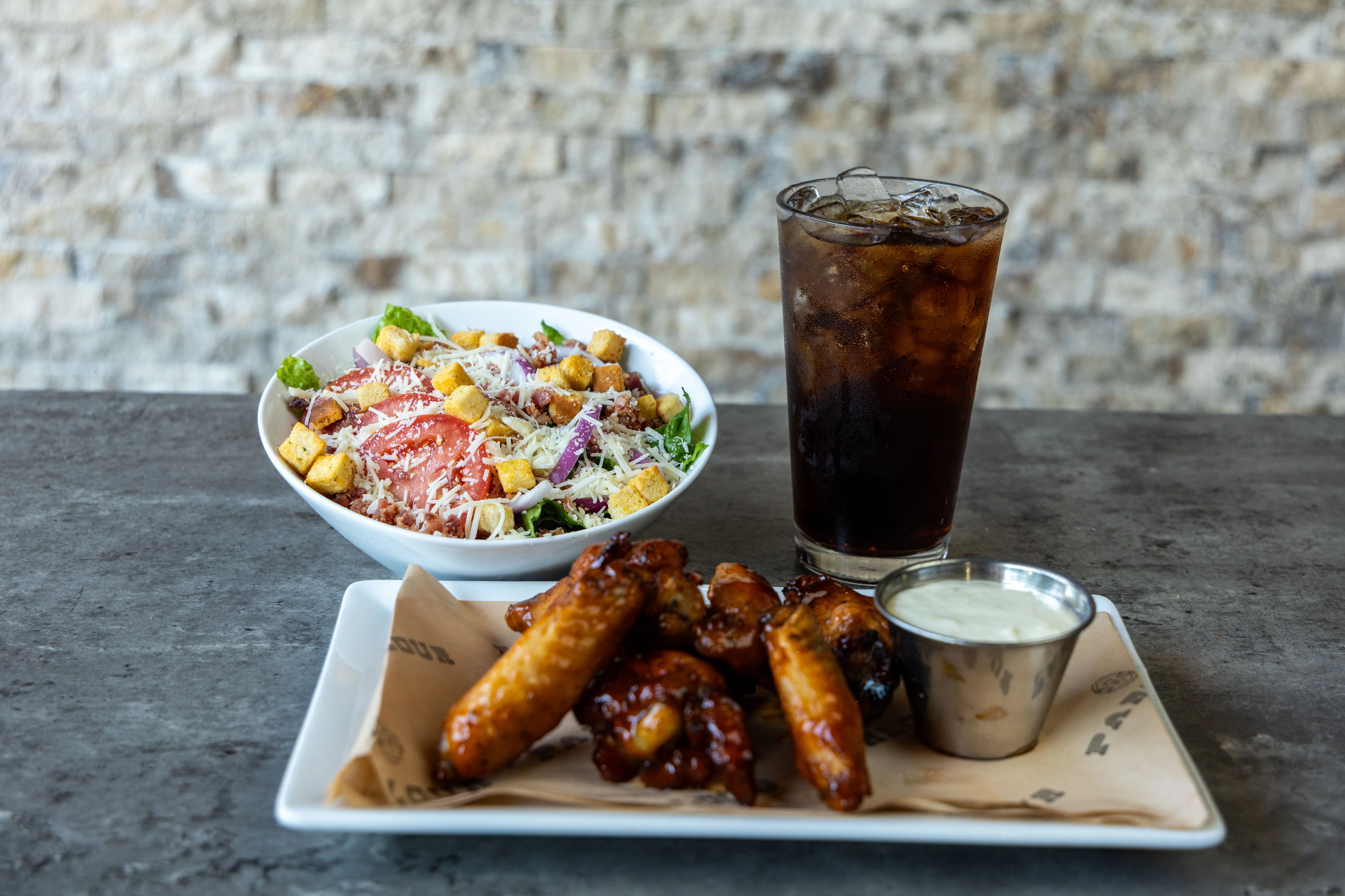 Crispy chicken wings with a side salad and iced cola