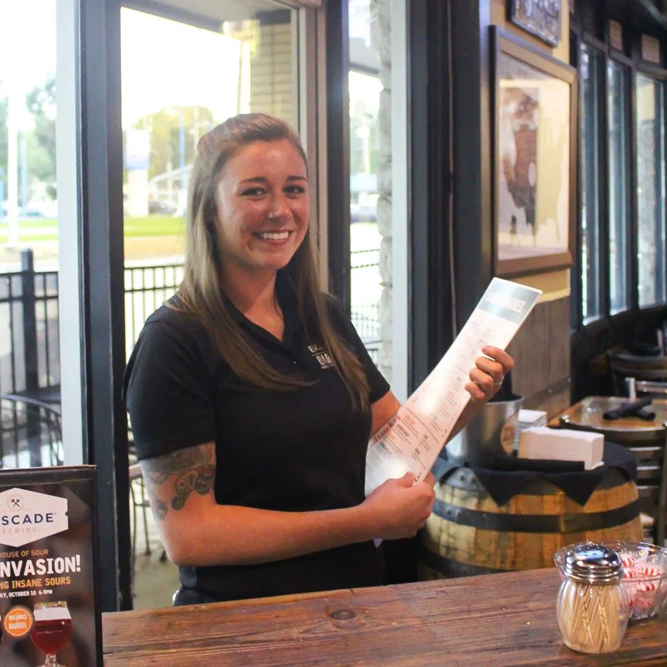 Smiling server holding a menu in a cozy restaurant
