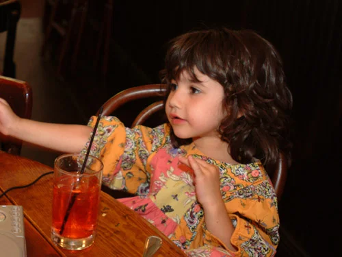 Child enjoying a drink in a cozy restaurant setting