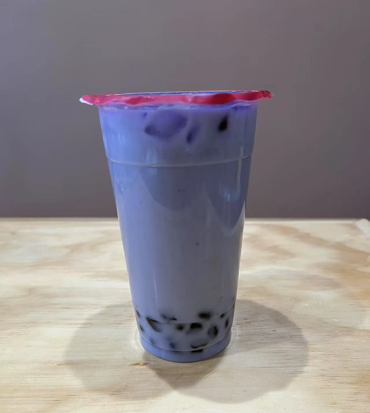 Purple taro milk tea with tapioca pearls in a clear cup