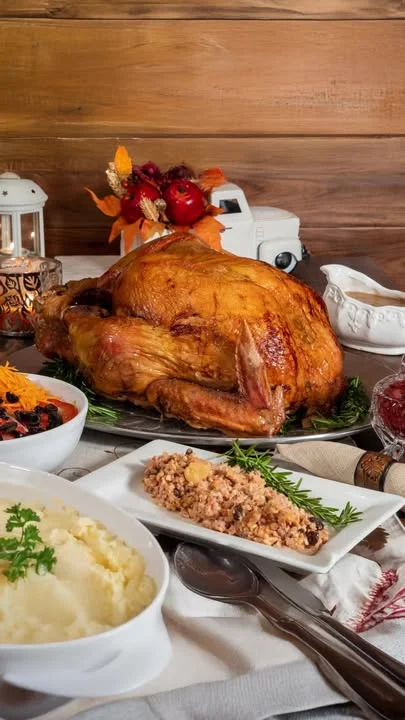 A beautifully roasted turkey served on a platter, surrounded by various side dishes including mashed potatoes, stuffing, and a colorful garnish.