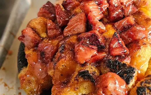 Delicious dessert topped with caramelized strawberries and bread pieces.