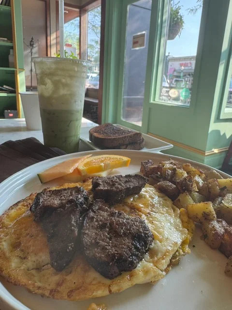 Hearty American breakfast with steak, eggs, potatoes, and fresh fruit