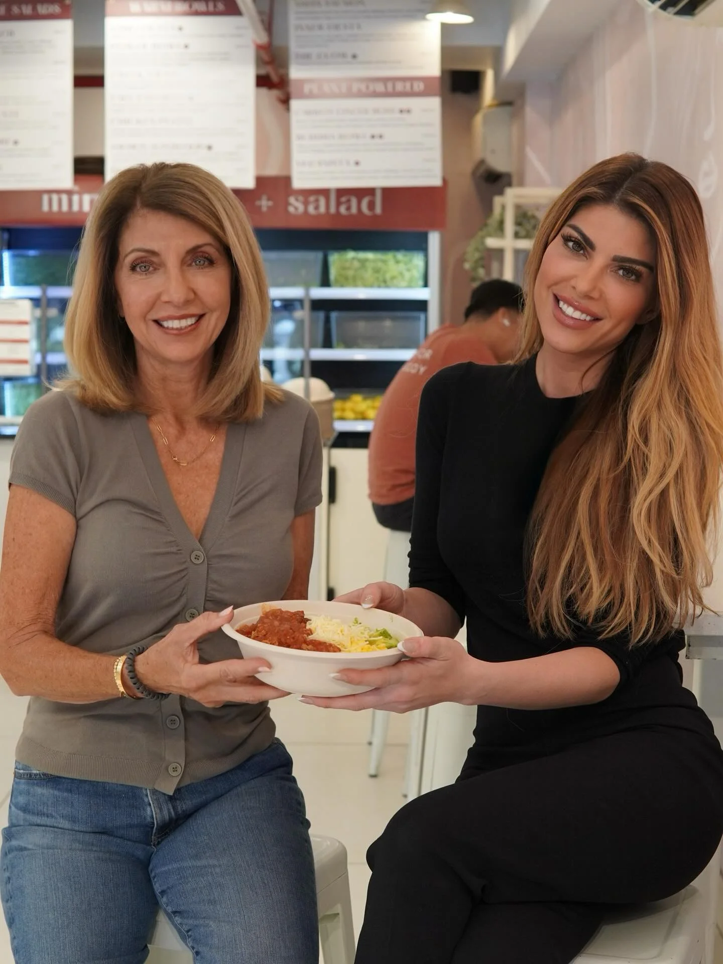 Two women sharing a vibrant Mexican rice bowl in a modern restaurant