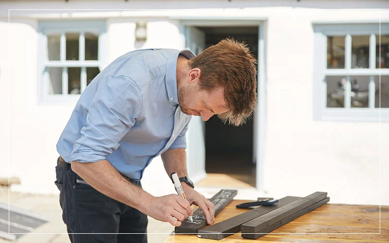 Person writing on a wooden board outdoors at a restaurant setting.