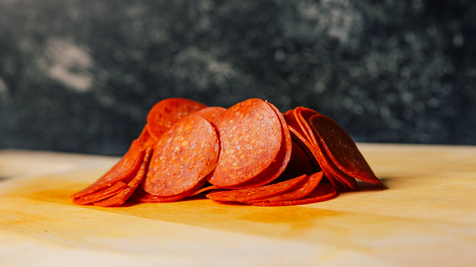 Sliced pepperoni for pizza preparation on a wooden board