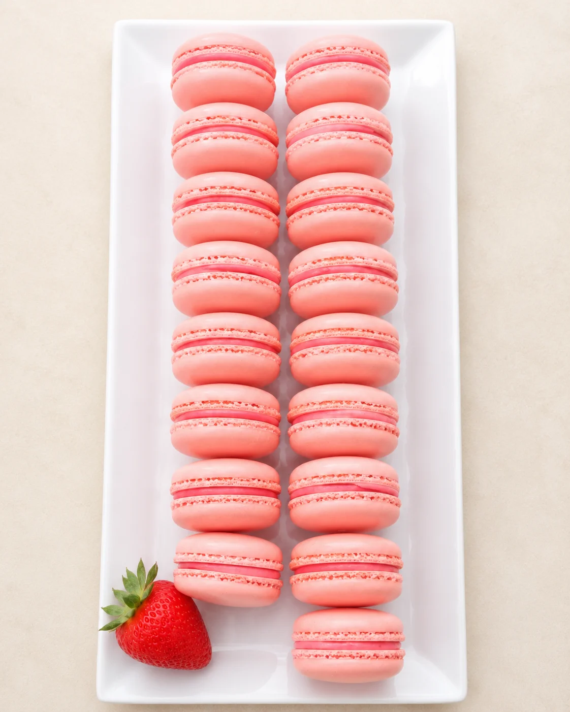Delicate French macarons in strawberry flavor on a white platter