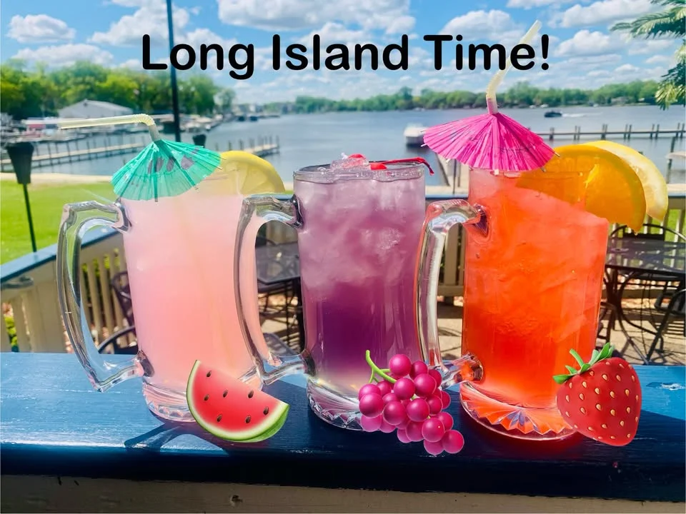 Colorful Long Island iced teas with fruit garnishes by the water