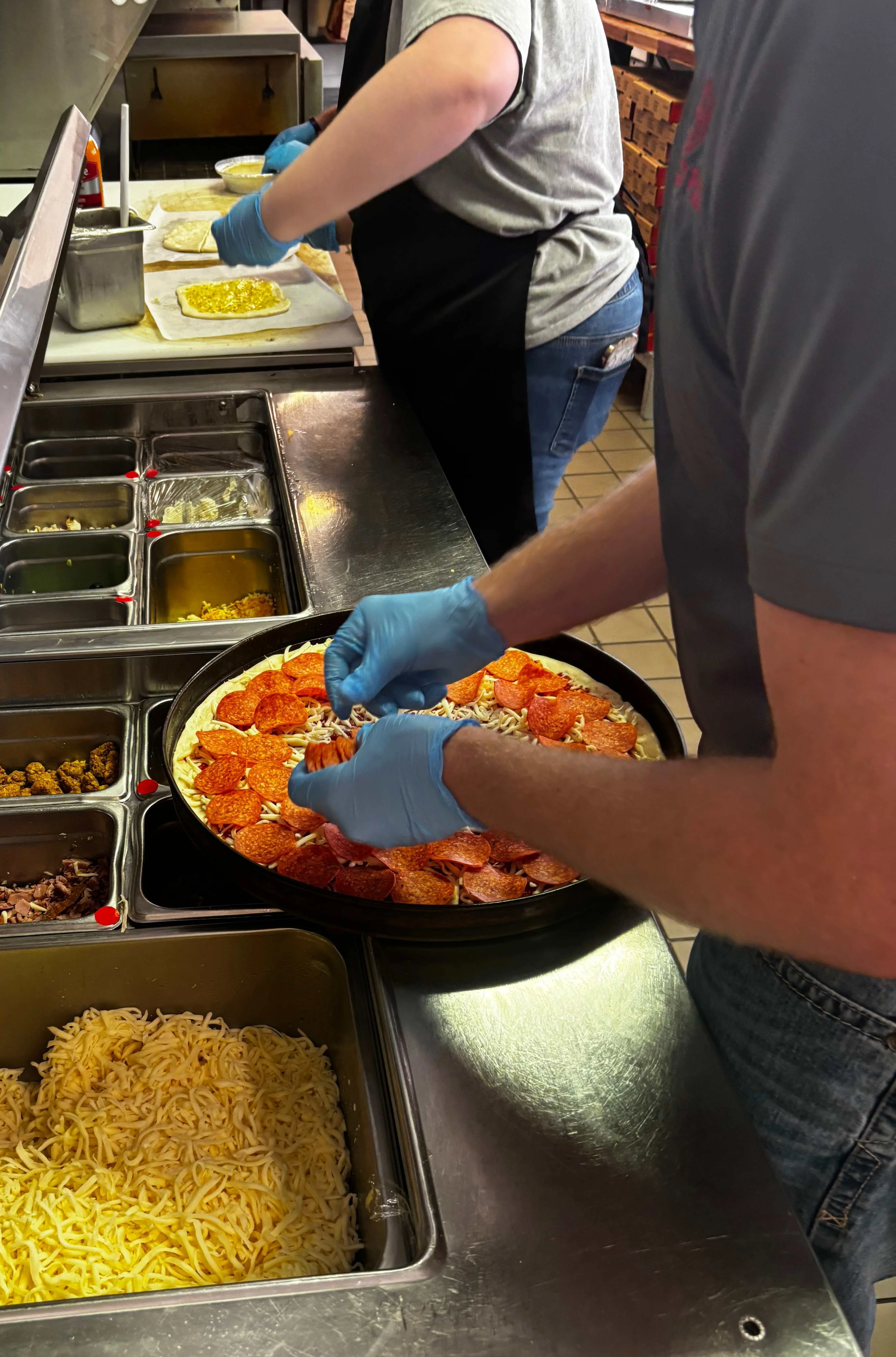 Preparing pepperoni pizza in a bustling kitchen