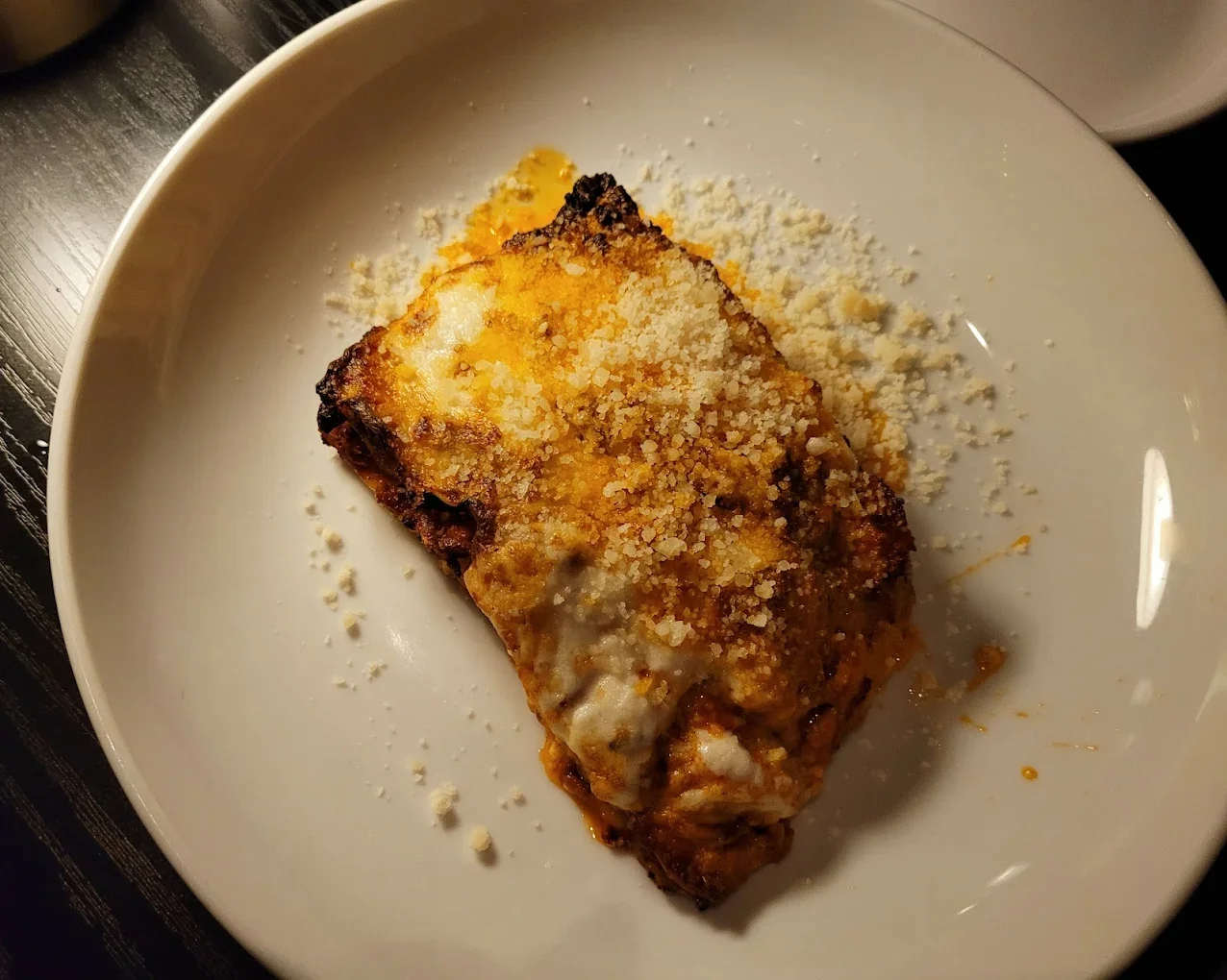 A plate of baked pasta topped with melted cheese and sprinkled with grated cheese, served warm.