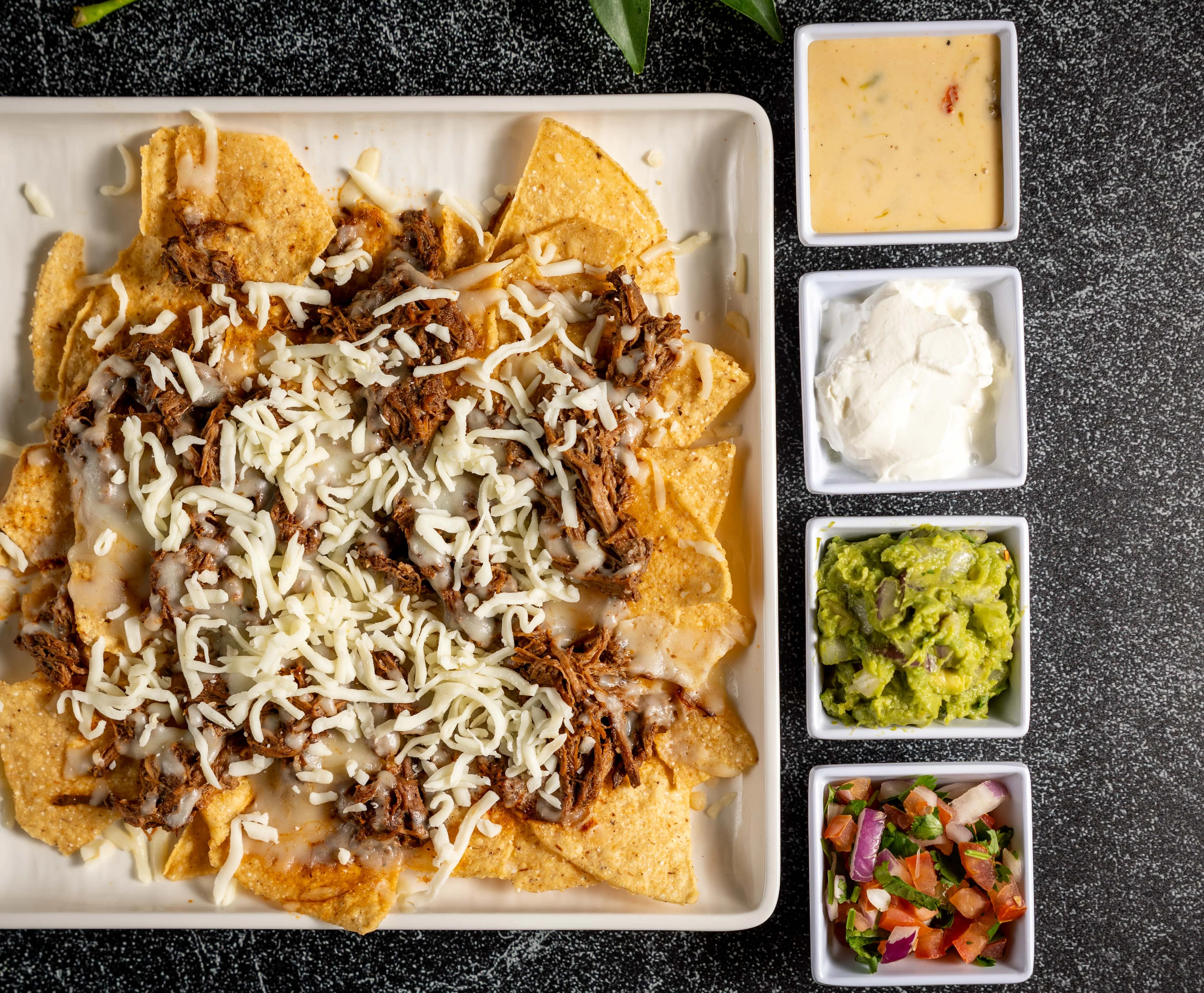 A top view of a delicious plate of nachos with toppings.