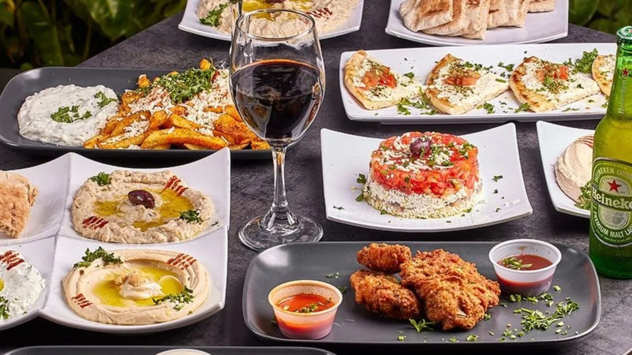 A variety of grilled meats, hummus platters, seafood, desserts, and wine.