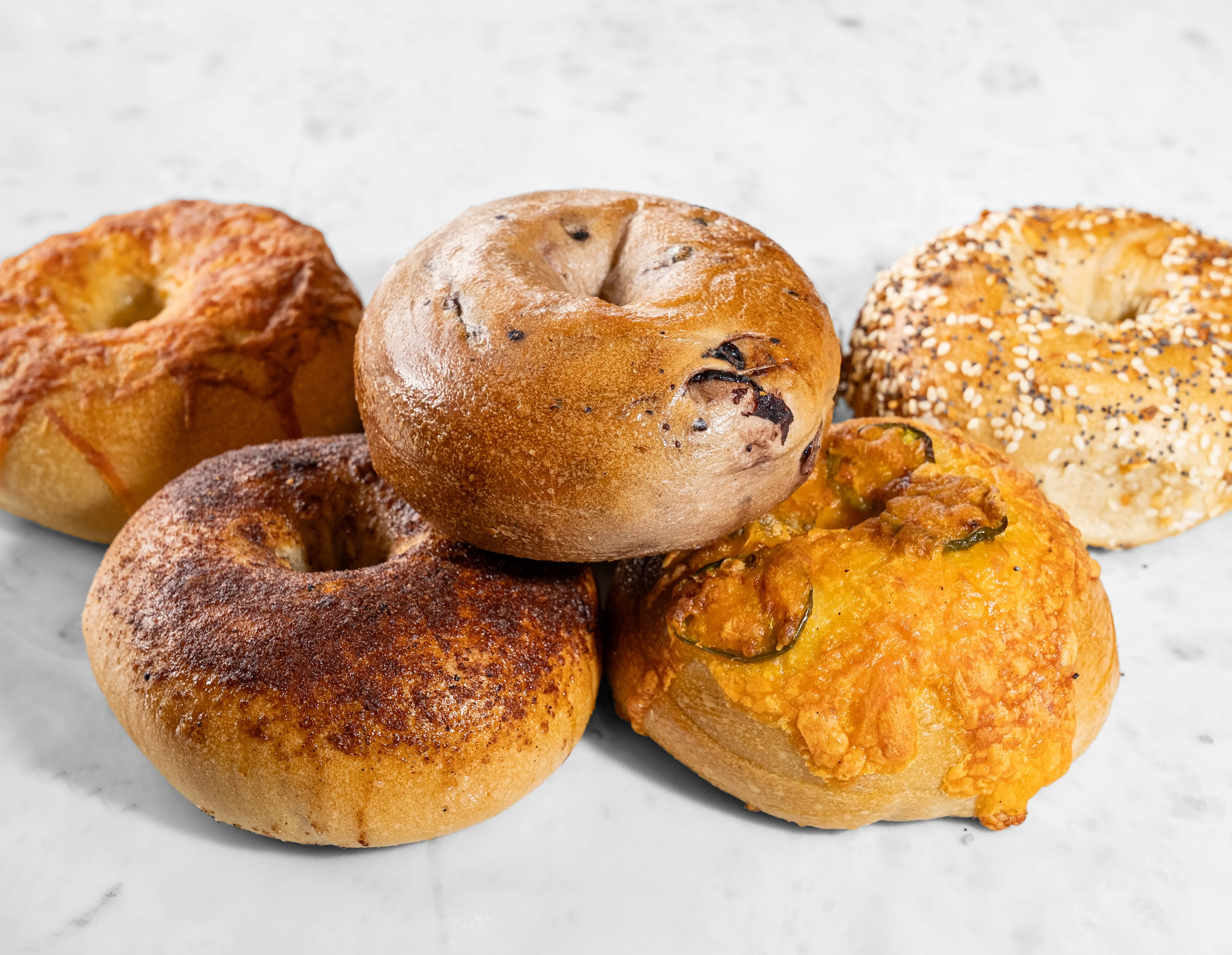 Half dozen assorted bagels displayed on a wooden board.