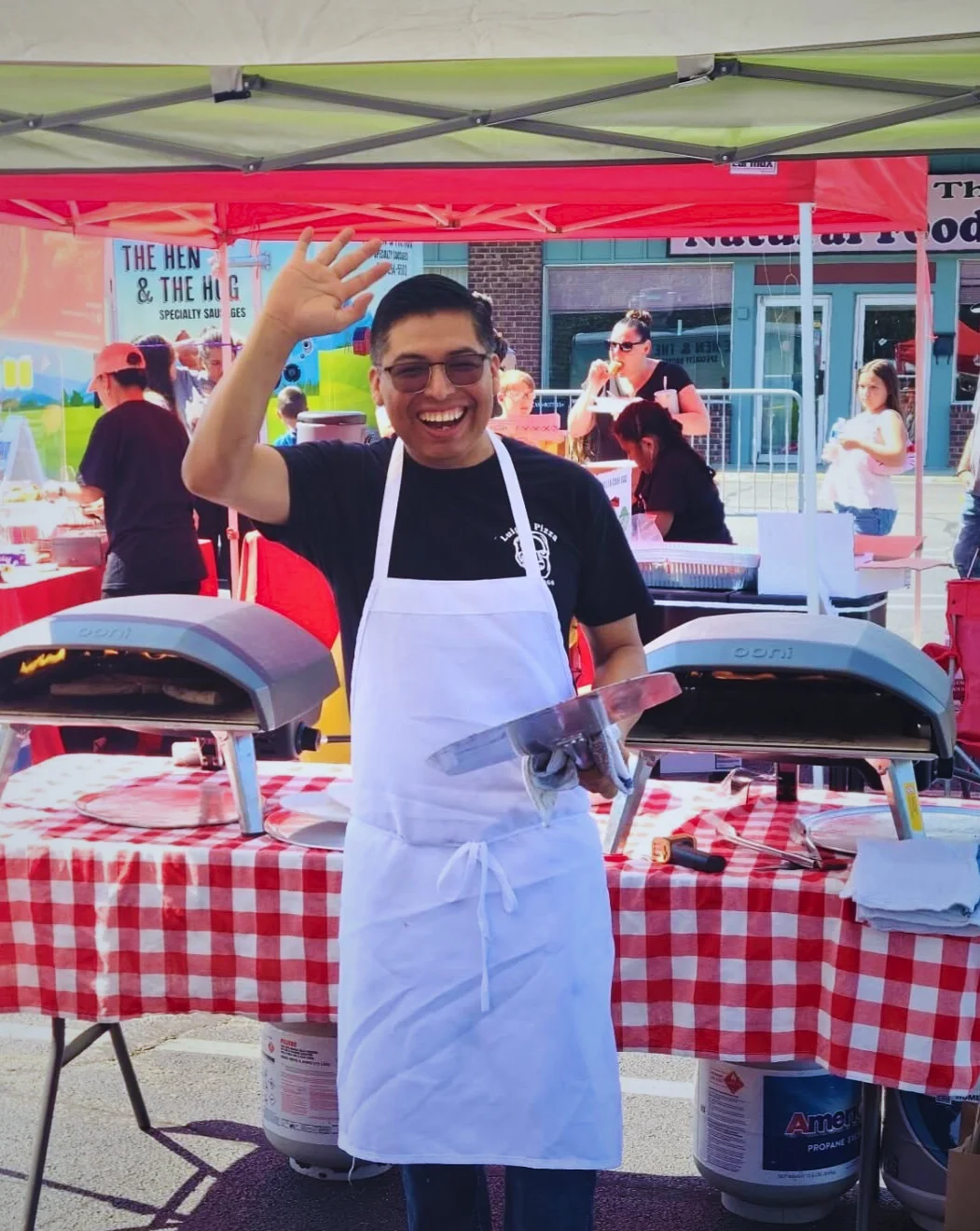 Chef smiling at a food festival with pizza ovens