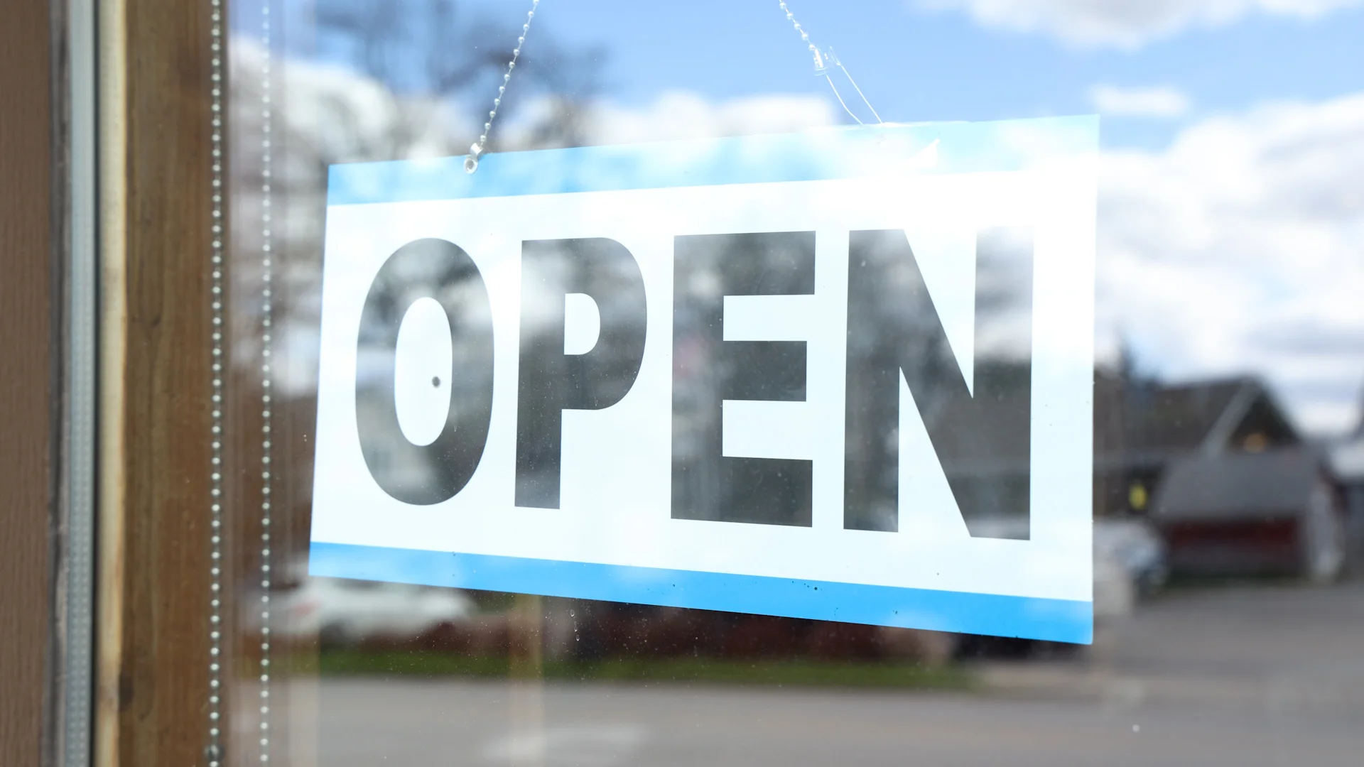 Open sign displayed in a restaurant window on a sunny day.