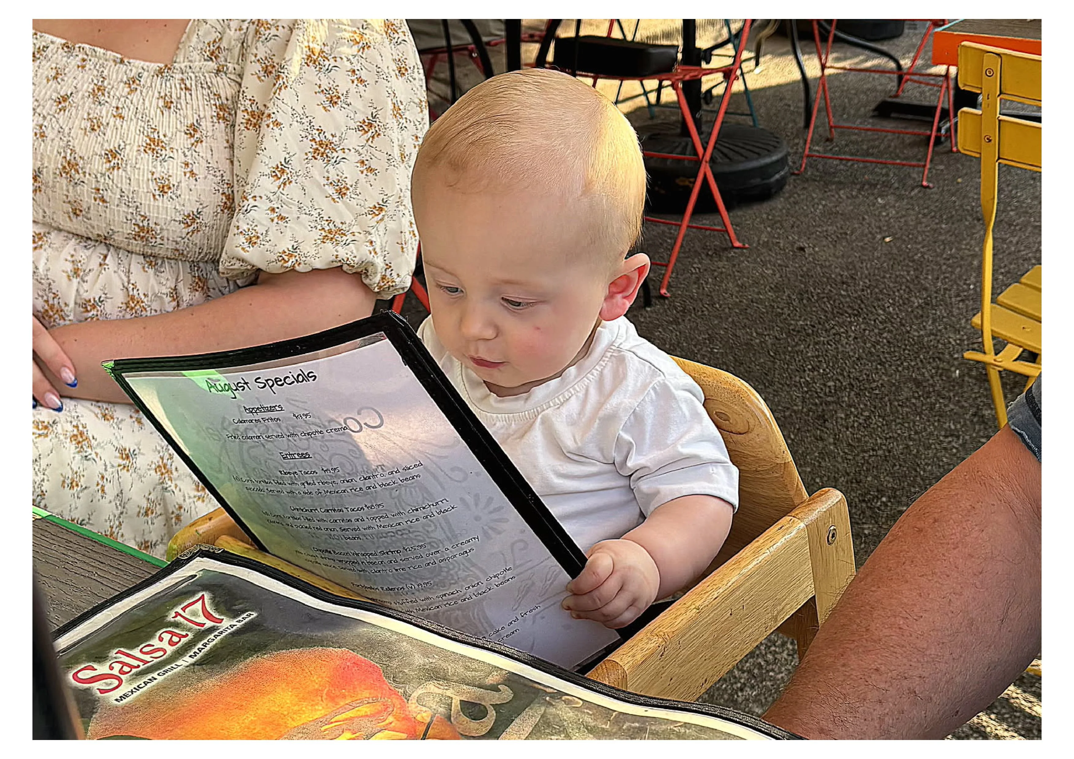 Child exploring a restaurant menu in a high chair