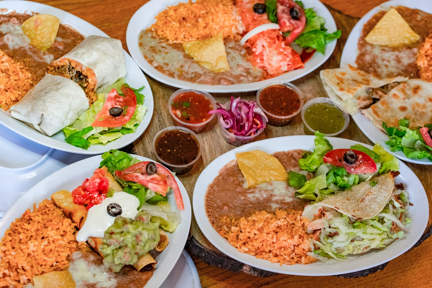 Colorful Mexican platter with burritos, rice, and salsas
