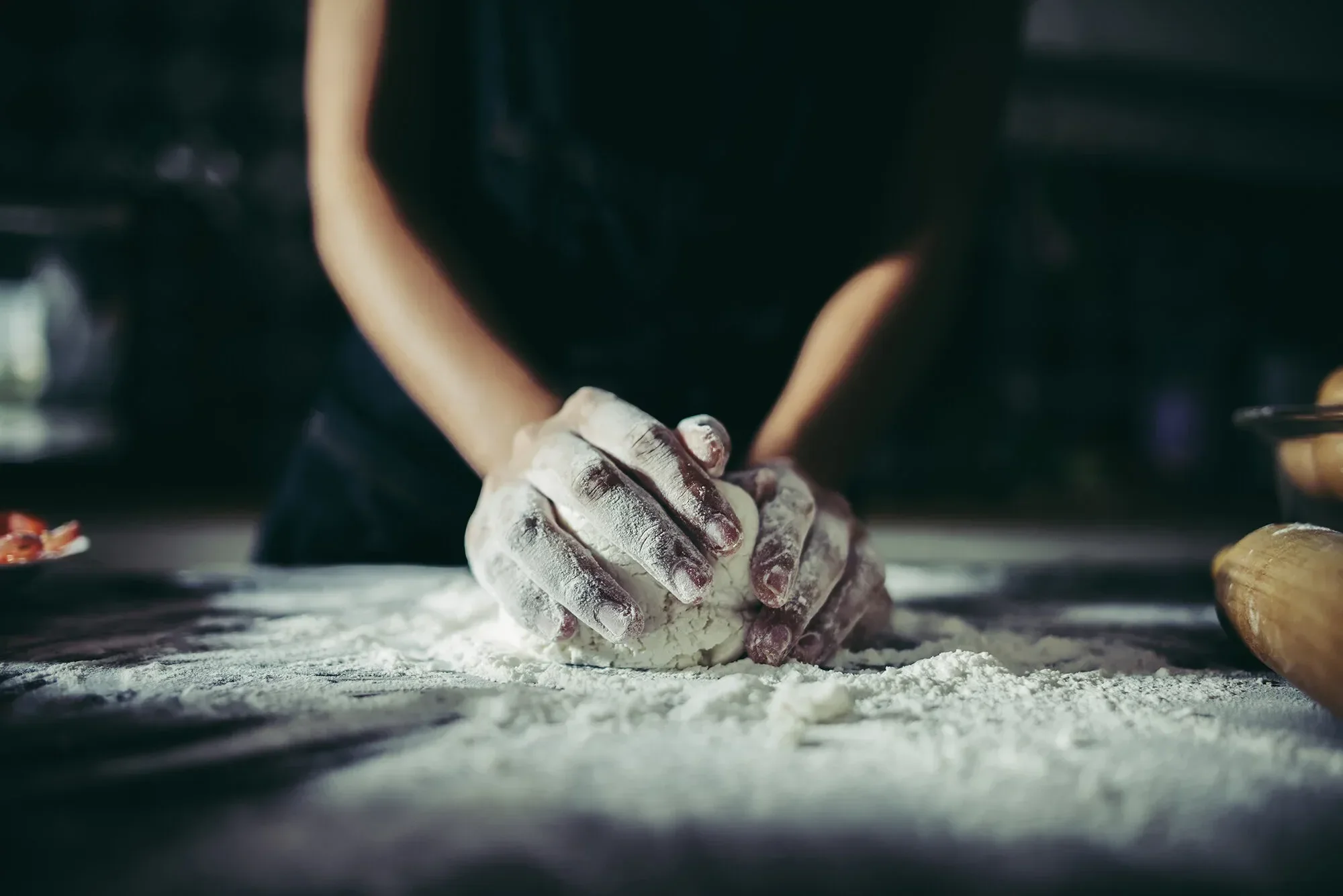 A pizza maker kneeding the dough