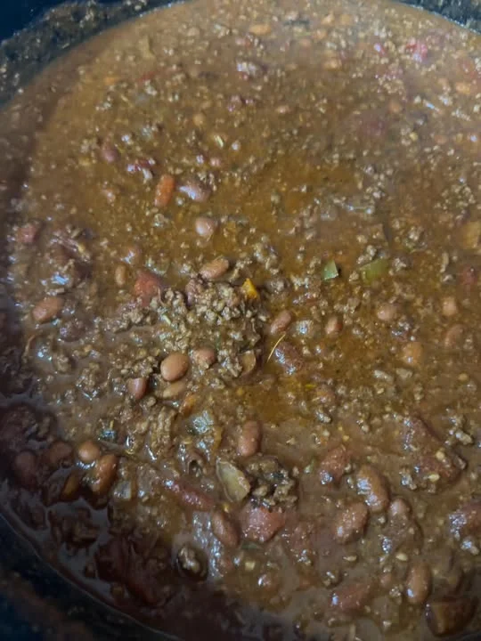 A pot filled with a rich and savory chili mixture, containing ground meat, kidney beans, tomatoes, and spices, simmering in a thick sauce.