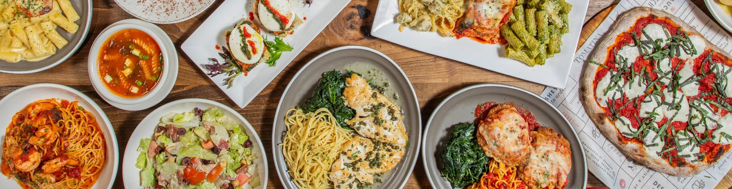 A Table displaying Tomatina food, Chicken Piccata, Chopped Italian Salad, Chicken Parmesan, Minestrone Soup, Pasta Trio, Cheese Pizza,