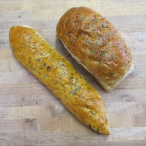 Freshly baked Italian focaccia and bread loaf on a wooden surface