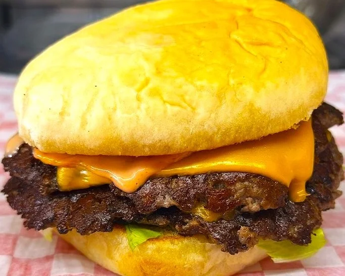 Close-up of a cheeseburger with lettuce on a bun.