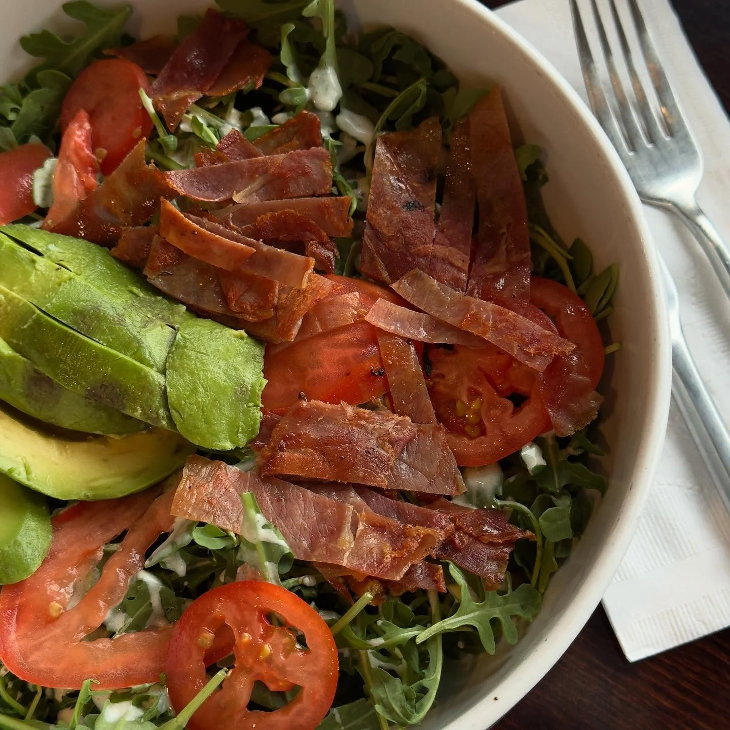 Fresh arugula salad with avocado and crispy bacon
