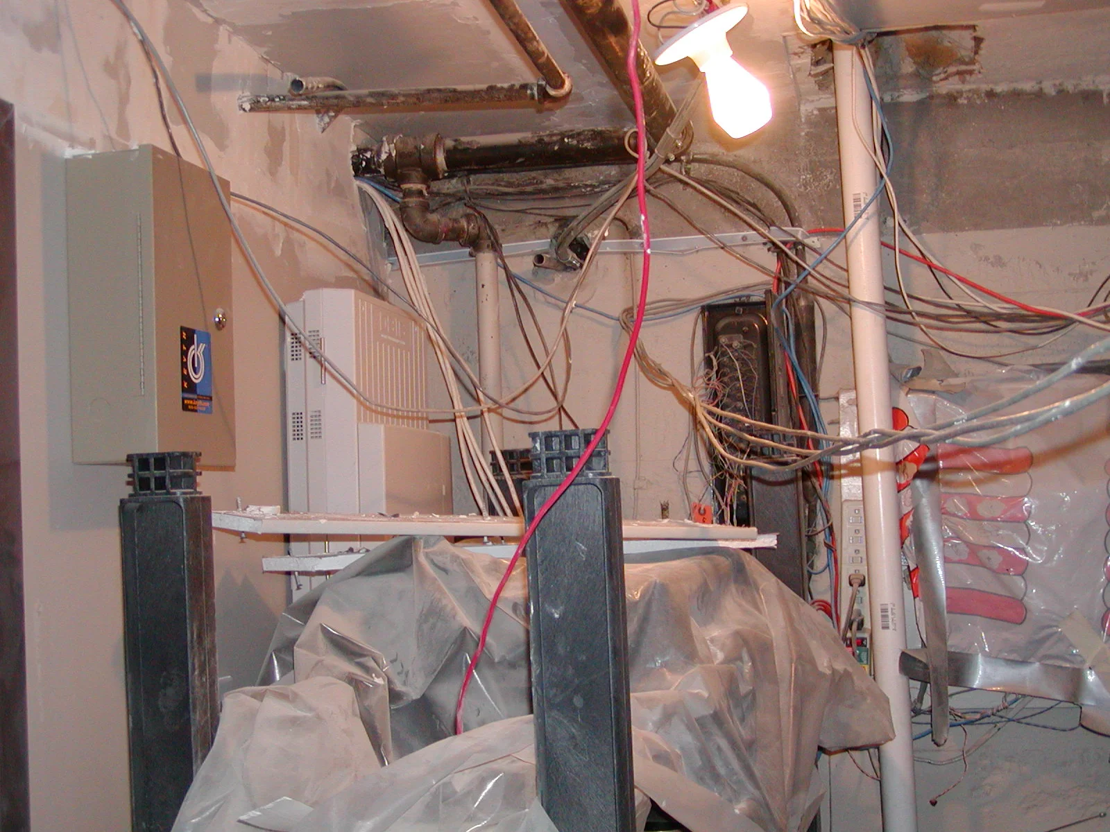 Cluttered utility room with exposed wires and equipment