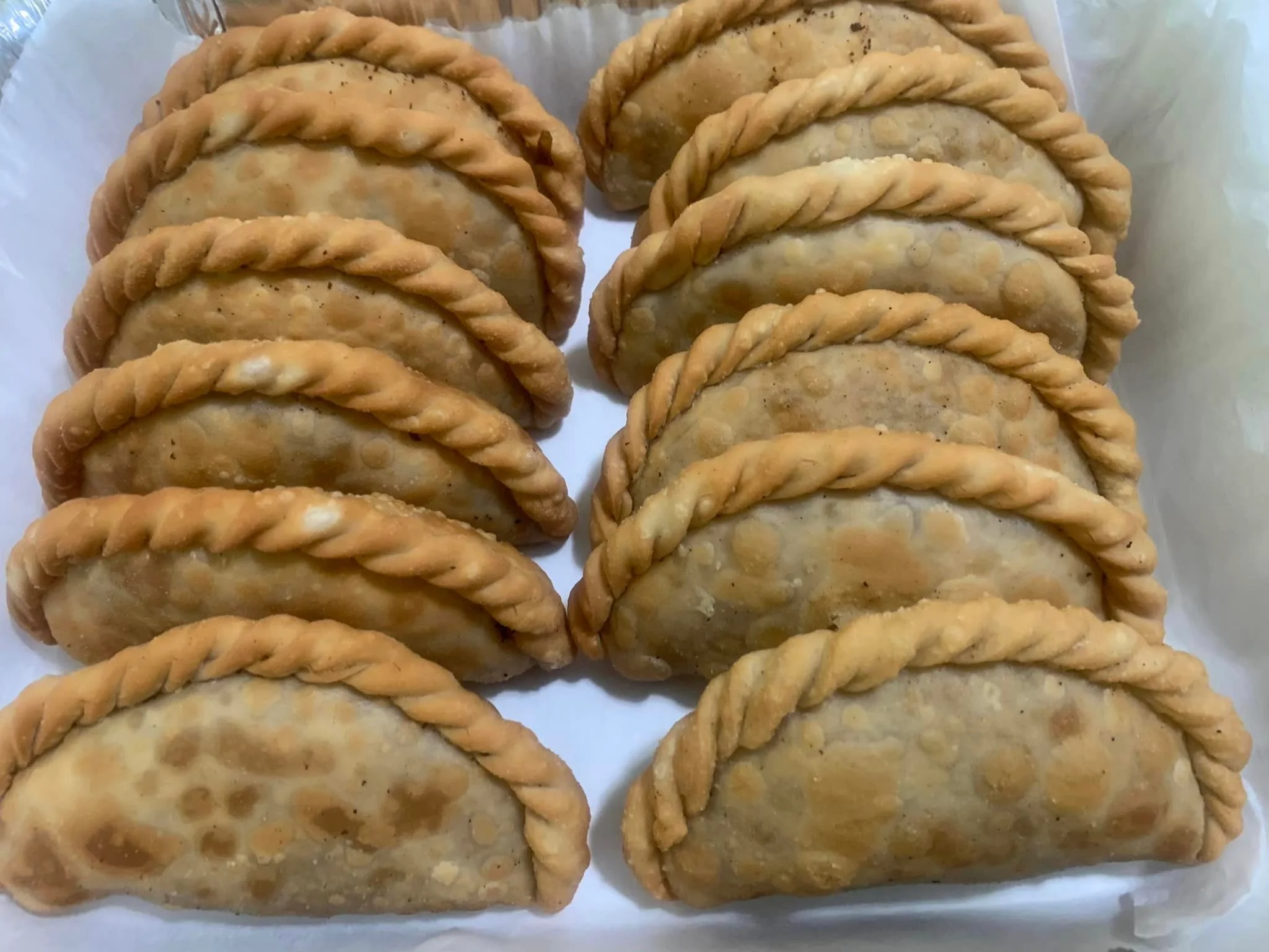 A tray filled with golden-brown, twisted pastries, neatly arranged in rows.